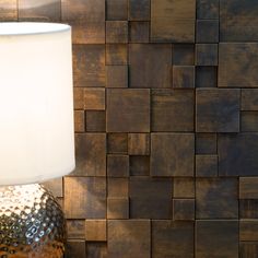 a lamp sitting on top of a table next to a wall covered in wooden tiles