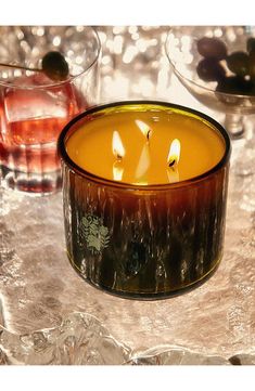 a candle is sitting on a table next to two glasses with drinks in them and ice