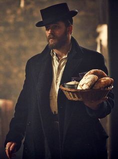 a man holding a basket with bread in it and wearing a top hat on his head