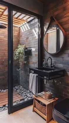 a bathroom with a sink, mirror and shower in it's stall area next to a brick wall