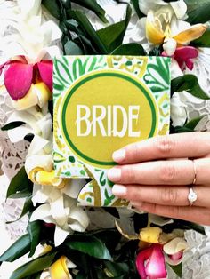 a person holding up a card with the word bride on it in front of flowers