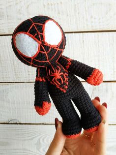 a hand holding up a crocheted spider man doll