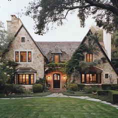 a large house with lots of windows and plants on the front lawn, surrounded by greenery