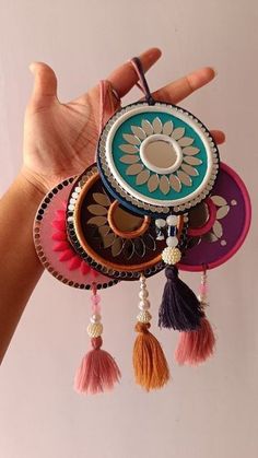 a hand holding a multicolored cell phone case with tassels hanging from it