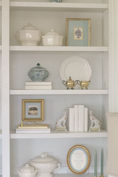 a white book shelf filled with books and other items on top of it's shelves