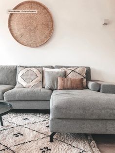 a living room with a gray couch and pillows on the floor next to a rug