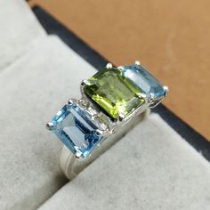 Three Stone Engagement Ring-Blue Topaz Ring-Peridot Gold Ring-14k Gold Wedding Ring-Peridot Gold Ring-Anniversary Gift For Her-For Bride ABOUT THE RING Gemstone - Peridot and Blue Topaz Gemstone shape - emerald/princess cut GEMSTONE  SIZE -6x8mm,wedding Ring 5x7mm Fast Shipping: It will take 1-8 business days to send out your item Material: 24k/20k/18k/14k/10k/9k Yellow Gold or Sterling Silver 925 About us- We are the manufacturers and suppliers of quality Gemstones and have specialized in jewel Anniversary Green Topaz Ring In Prong Setting, Green Three Stone Gemstones For Anniversary, Green Multi-stone Sapphire Promise Ring, Green Topaz Ring With Prong Setting For Anniversary, Green Topaz Ring With Emerald Cut And Accent Stones, Anniversary Green Topaz Ring With Prong Setting, Green Emerald Cut Topaz Ring With Accent Stones, Green Emerald-cut Topaz Ring With Accent Stones, Emerald Cut Green Topaz Ring With Accent Stones