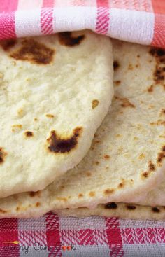 three pita breads sitting on top of a red and white checkered cloth