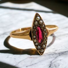 Introducing our exquisite Victorian Era ring, a timeless masterpiece that captivates with its elegance and grace. Crafted from 14K rose gold, this ring features a stunning central marquise-shaped pink tourmaline, radiating with a deep blush hue reminiscent of romance and refinement.  Surrounding the tourmaline are lustrous pearls, each one carefully selected to complement the gemstone's beauty and add a touch of sophistication.  With intricate Victorian-era detailing and craftsmanship, this ring Luxury Marquise Ruby Ring For Wedding, Luxury Pink Marquise Ring, Pink Marquise Ruby Ring For Formal Occasions, Formal Marquise Pink Ruby Ring, Formal Pink Marquise Ruby Ring, Fine Jewelry Pink Marquise Ruby Ring, Pink Marquise Ruby Ring Fine Jewelry, Pink Marquise Ring For Formal Occasions, Pink Marquise Rose Cut Diamond Rings