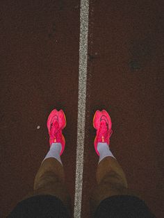 the feet of a person wearing pink shoes standing in front of a cross walk line