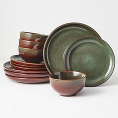 a stack of green and brown dishes sitting next to each other on a white surface