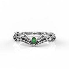 a white gold ring with an emerald stone in the center and two leaves on each side