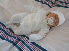 a baby wearing a pacifier laying on top of a bed