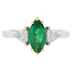 Here we have a magnificent emerald and diamond three-stone ring that is crafted in solid platinum with an 18k yellow gold center that features a gorgeous, GIA certified, natural emerald stone. The solitaire displays a very clean and truly incredible vivid green color with wonderful amount of shine due to its brilliant cutting style. This marquise cut stone is neatly prong set at the center and shows a very attractive size, weighing exactly 1 carat. It is elegantly flanked by two, very fine quality, trillion cut diamonds in which perfectly complement the center stone, showing spectacular amount of sparkle and brilliance, totaling 0.58 carats in weight. The amazing color of the emerald along with the elegant design make this ring truly stand out and hard not to fall in love with. This specta Trillion Diamonds, 3 Stone Ring, 3 Stone Rings, Emerald Stone, Three Stone Rings, Marquise Cut, Natural Emerald, 1 Carat, Three Stone