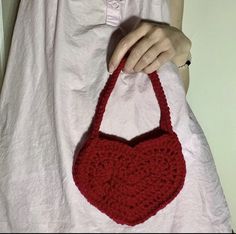 a woman is holding a crocheted red purse