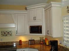 a kitchen with white cabinets and granite counter tops is seen in this image, there are candles on the counter