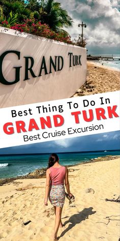 a woman walking on top of a sandy beach next to the ocean in front of a grand turk sign