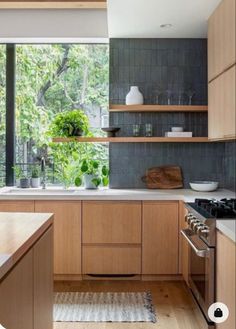 a kitchen with wooden cabinets and white counter tops next to an open window that looks out onto the woods