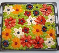 a tray filled with fruit and flowers on top of a table