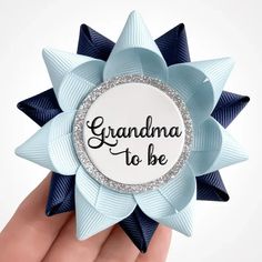 a hand holding a blue and white flower with the words grandma to be on it