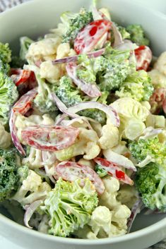 a white bowl filled with broccoli and red onion salad on top of a table