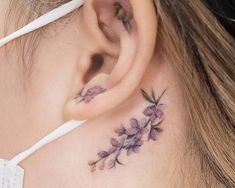 a woman's behind the ear tattoo with purple flowers on her left side ribcage