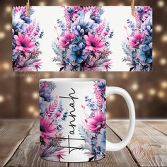 two mugs with flowers on them sitting on a wooden table next to string lights