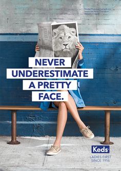 a woman sitting on top of a bench holding up a sign that reads never underestimite a pretty face