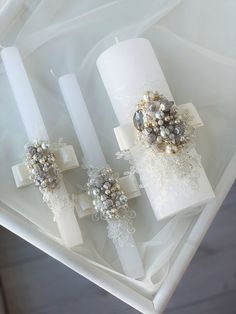 three white candles with bows and pearls on them