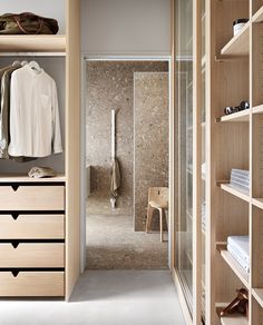 a walk in closet with wooden shelves and drawers