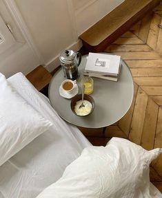 a small table with some food on top of it next to pillows and a book