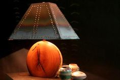 a table lamp sitting on top of a wooden table next to two bowls and cups