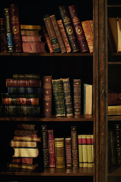 a book shelf filled with lots of books next to a wooden framed wall mounted clock