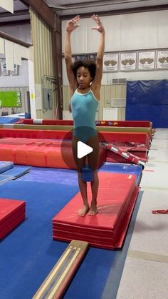 a woman standing on top of a red and blue trampoline in a gym