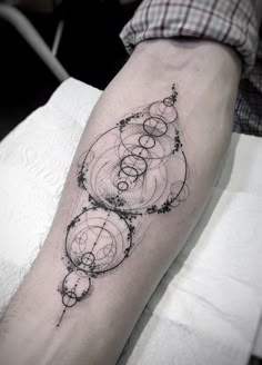 a person with a tattoo on their arm that has circles and dots all over it