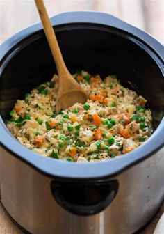 a wooden spoon in a slow cooker filled with rice and vegetables