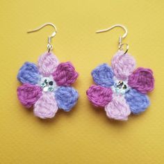 crochet flower earrings with swarong crystals on them sitting on a yellow surface