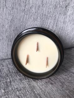 a white candle with two small sticks sticking out of it's center sitting on a gray couch