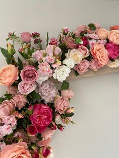 an arrangement of pink and white flowers on a shelf