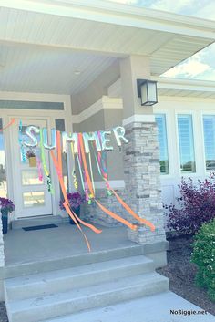 a front porch decorated for summer with streamers on the door and flowers in pots