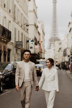 a man and woman walking down the street in front of the eiffel tower