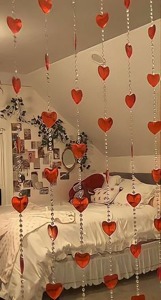 a bed with lots of hearts hanging from it's sides and on the ceiling