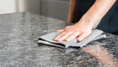 a person wiping up with a cloth on top of a counter