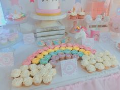 a table topped with lots of cupcakes next to a cake and other treats