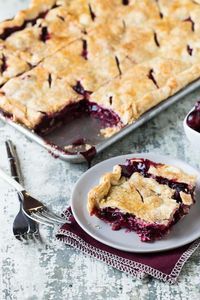 a piece of pie sitting on top of a plate next to a bowl of cherries