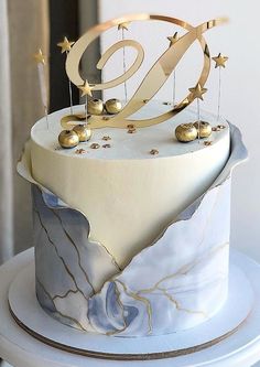 a white and gold birthday cake with stars on the top is sitting on a table