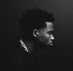 a black and white photo of a young man with dreadlocks on his head