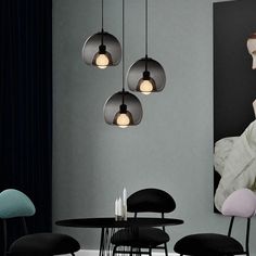 an image of a modern dining room setting with black chairs and round lights hanging from the ceiling