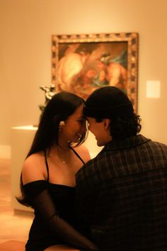 a man and woman sitting next to each other in front of a painting on the wall