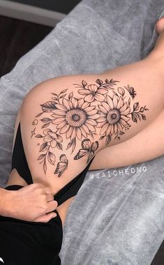 a woman laying on top of a bed covered in sunflowers and bees tattoo